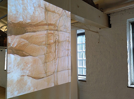 A projected image of rocks made with machine learning software, in an old mill building